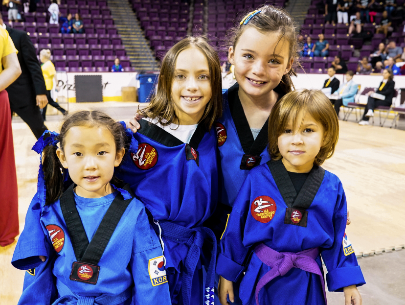 Four child students smiling dressed in blue taekwondo garb